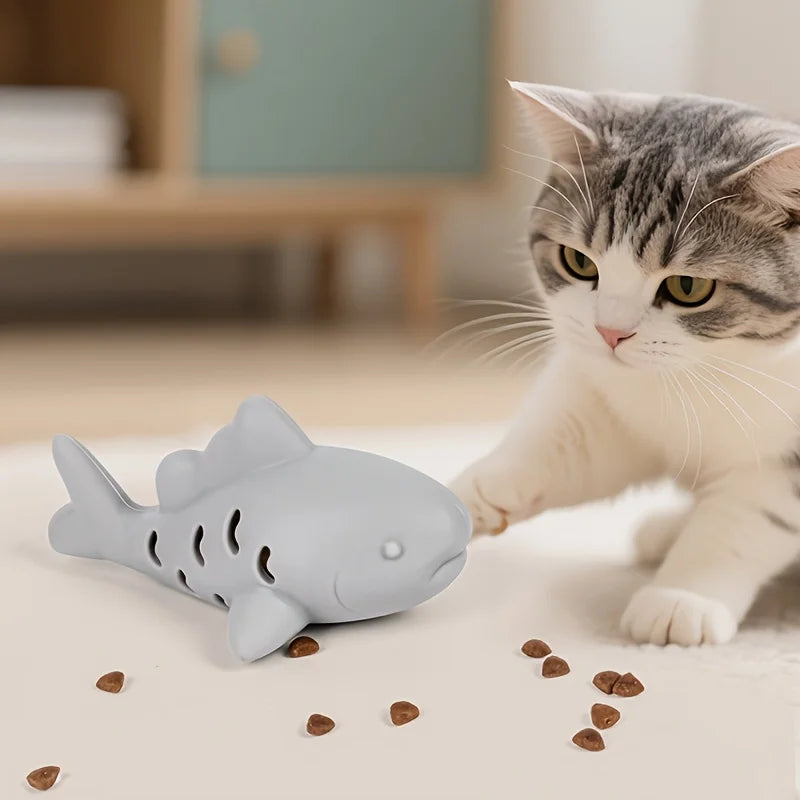 Cat playing with JooJeo Shark interactive treat dispenser toy, engaging with treats on the floor.