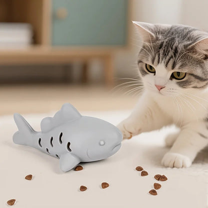 Cat playing with JooJeo Shark interactive treat dispenser toy, engaging with treats on the floor.